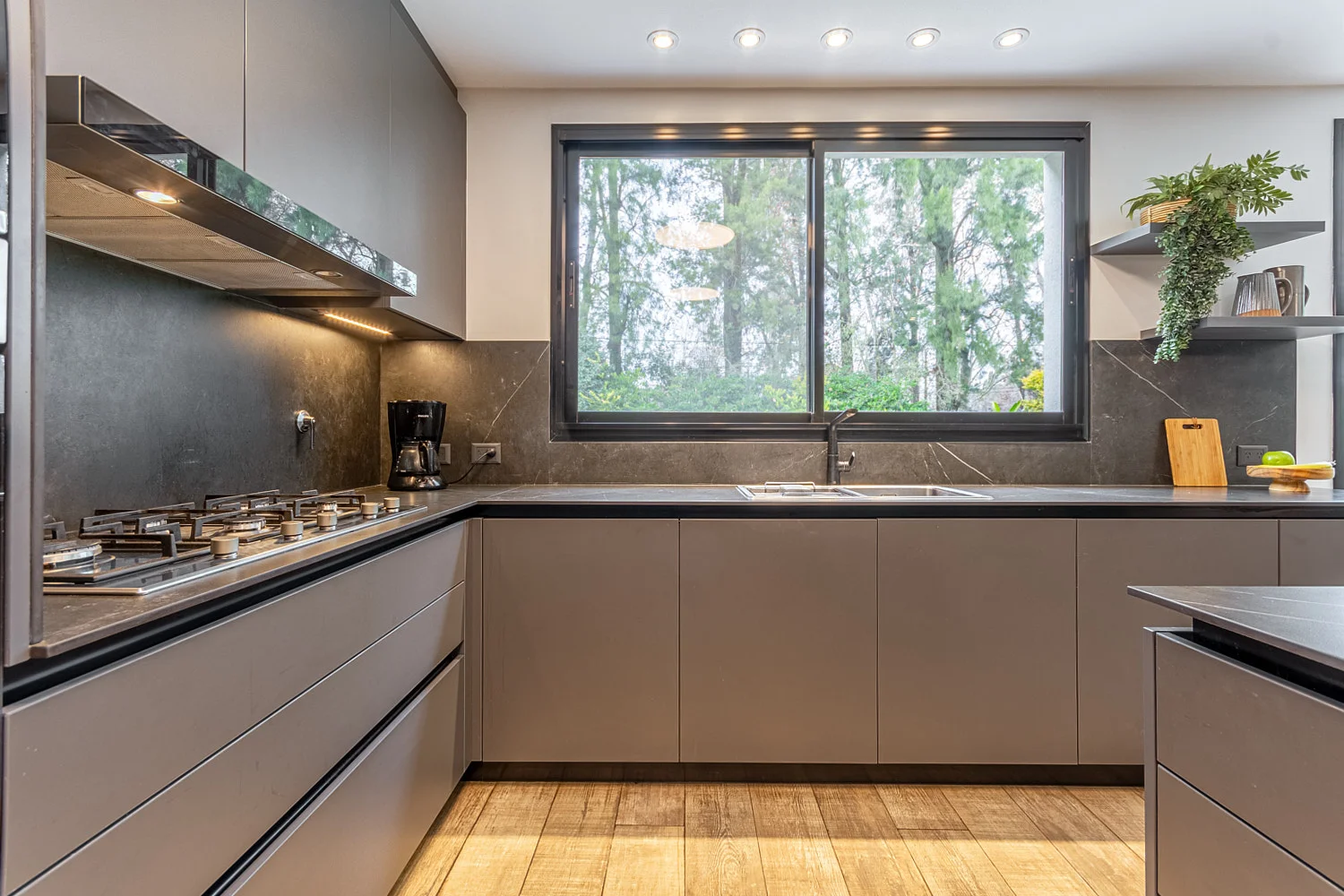 Cocina en L gris con ventanal y mesada oscura