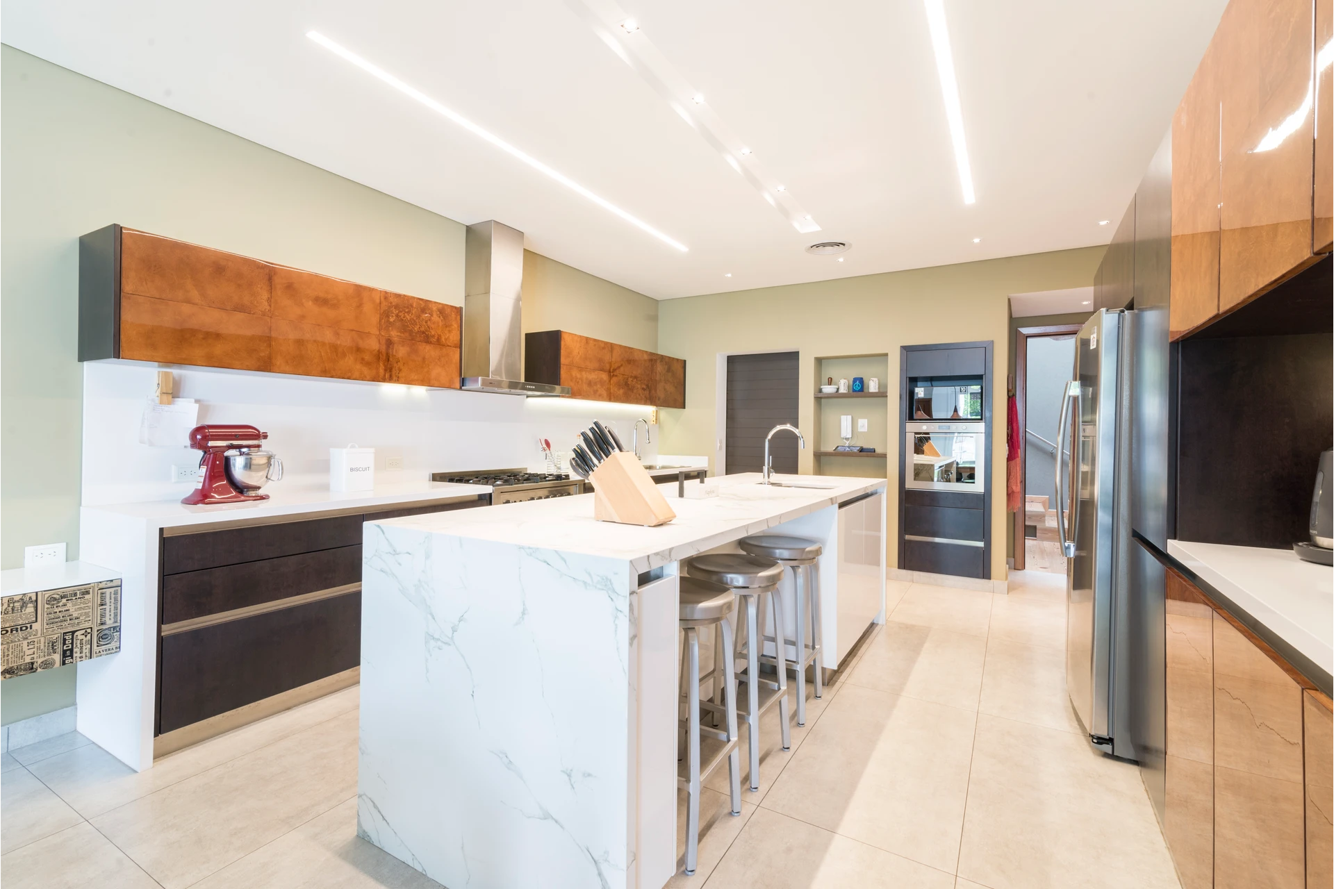 Cocina con isla blanca veteada y alacenas de madera