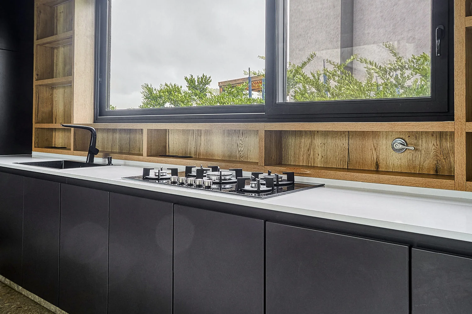 Cocina con frentes negros y estantes de madera