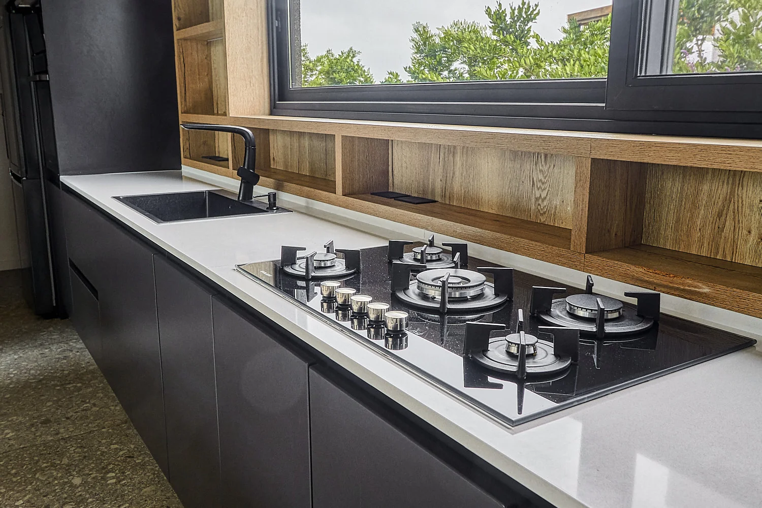 Cocina lineal negra con anafe y ventana